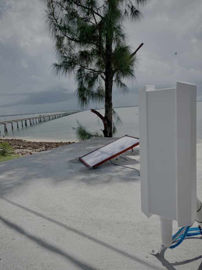 Starlink terminal on a rooftop near the coast, a long bridge in the distance