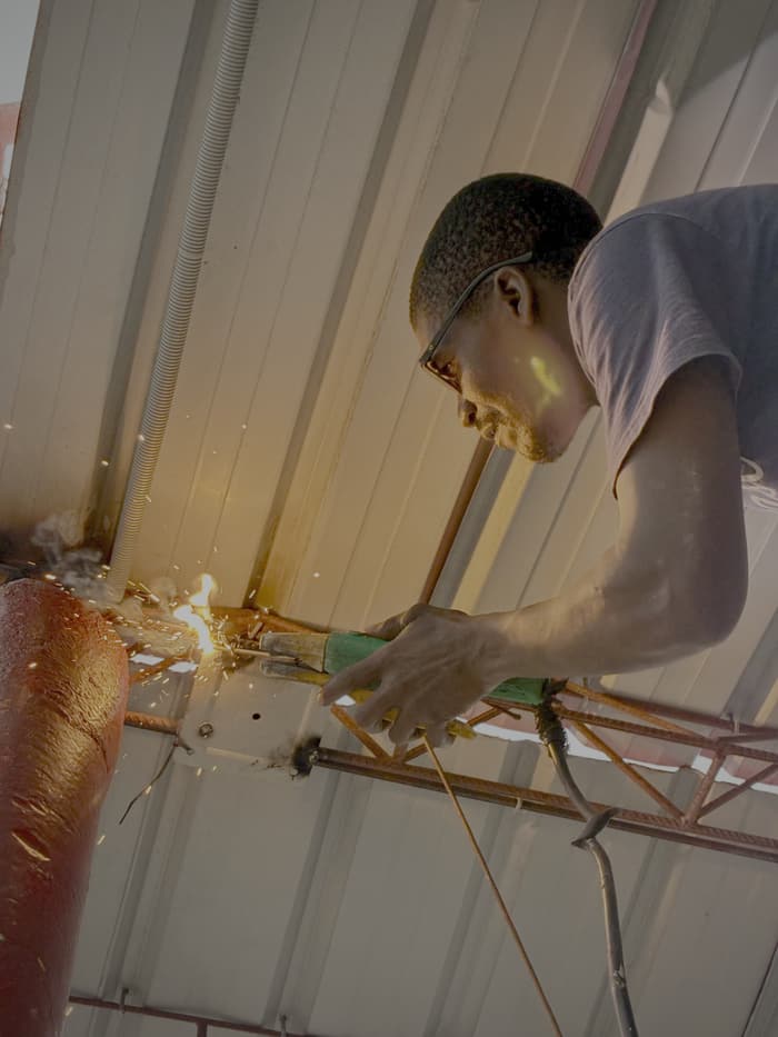 Technician welding a steel mast section on site