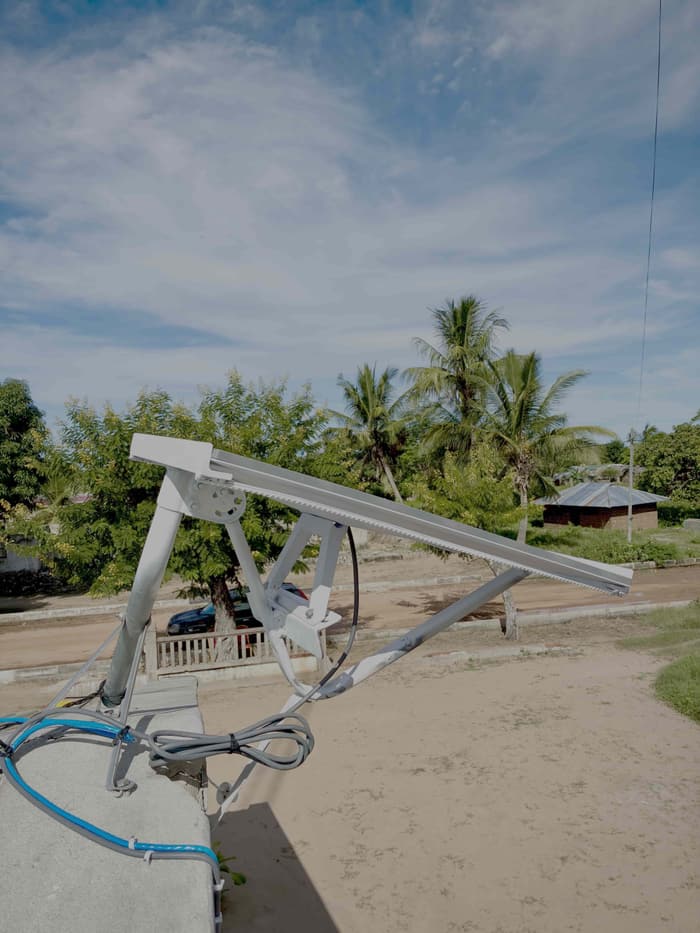 Starlink terminal on an angled steel frame, palm trees behind